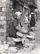 Tr&uuml;mmerfrau beim Steineklopfen