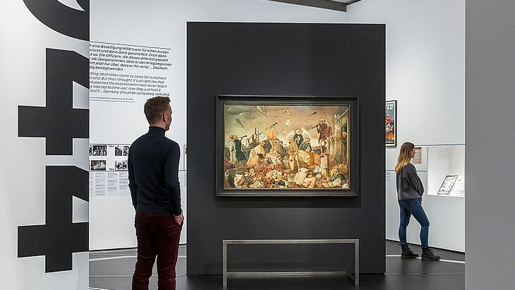 Besucher betrachten Ausstellungsstücke und Wandbilder in einem modernen Museum.