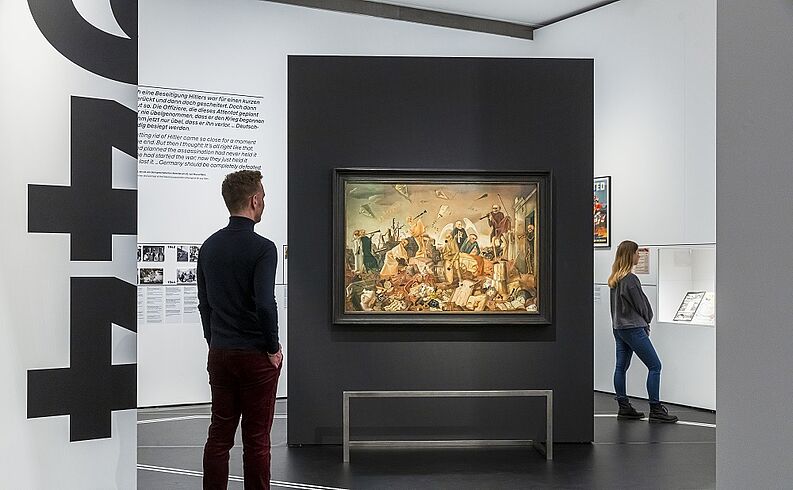 Besucher betrachten Ausstellungsstücke und Wandbilder in einem modernen Museum.