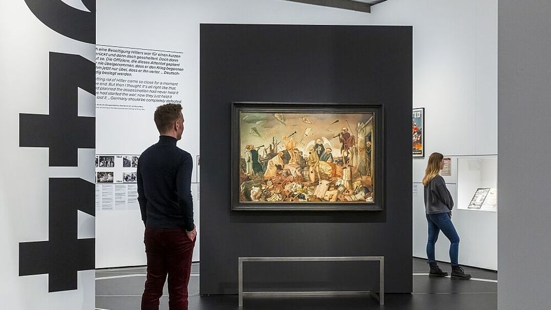 Besucher betrachten Ausstellungsstücke und Wandbilder in einem modernen Museum.
