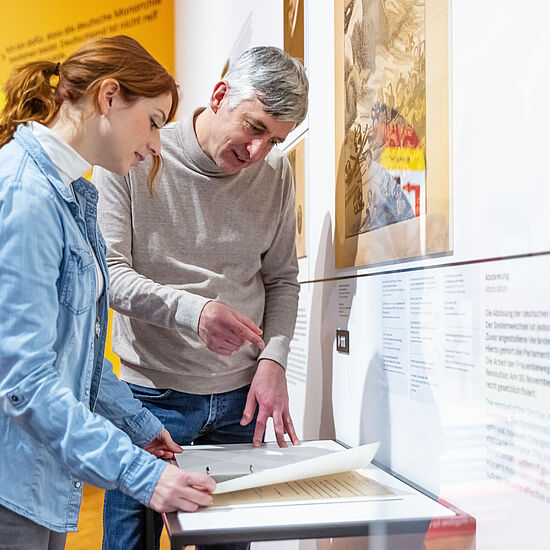 Eine Frau und ein Mann Blättern in einem Ordner und reden.