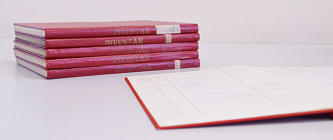 Rote Inventarbücher auf einem Tisch.