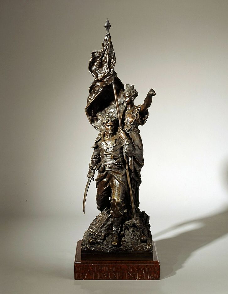 Bronzeskulptur von Mann und Frau mit Flagge.