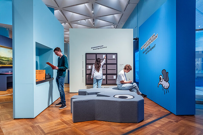 Personen beschäftigen sich mit Objekten und Materialien in der Ausstellung.