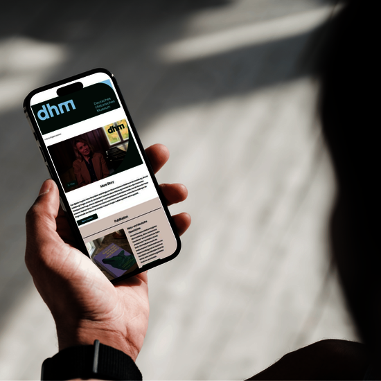 Eine Person hält ein Smartphone in der Hand und betrachtet den Newsletter des Museums.