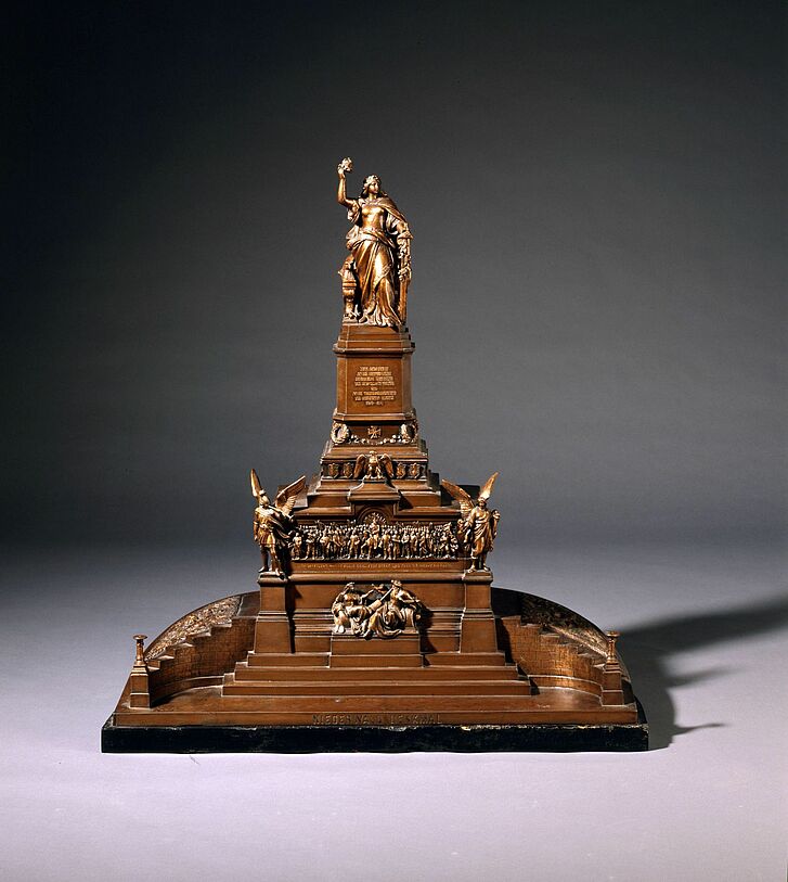 Skulptur mit Treppen und Figuren.