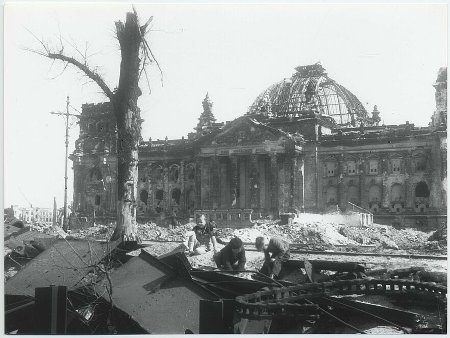 Spielende Kinder vor dem von Bomben zerstörten Reichstag.