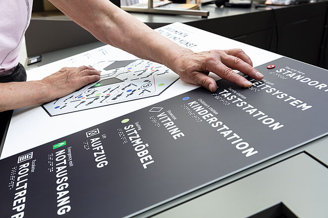 Eine Tafel mit Blindenschrift wird von einer Person benutzt.