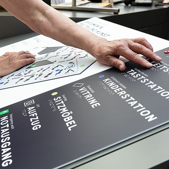 Eine Tafel mit Blindenschrift wird von einer Person benutzt.