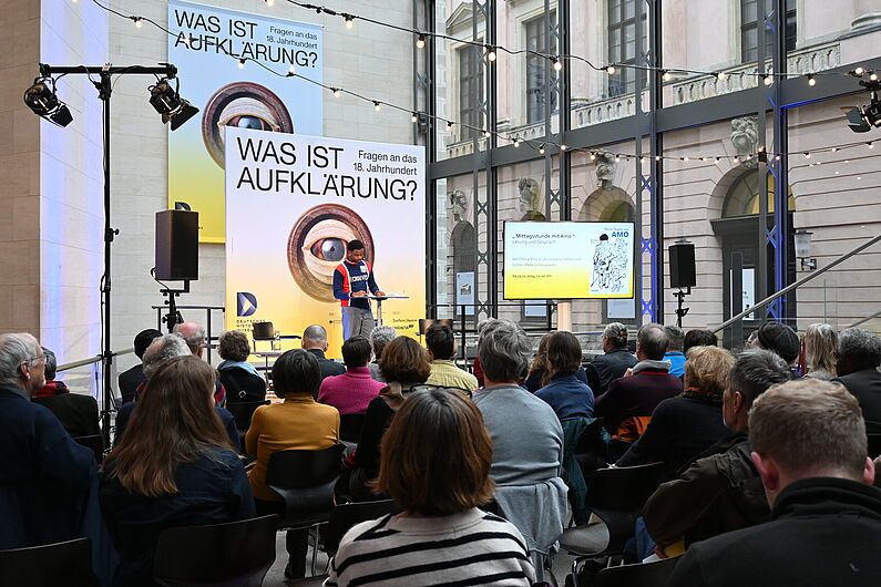 Ein Mann steht auf der Bühne vor dem Publikum.