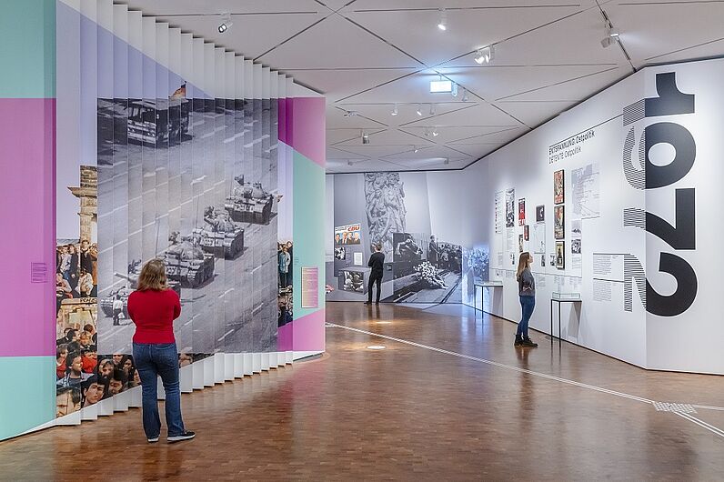 Mehrere Personen betrachten eine bunte, moderne Ausstellung in einem Museumsraum.