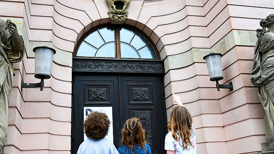 Drei Kinder stehen vor einem Gebäude