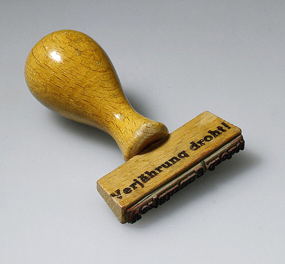 Stempel der Zentralen Stelle der Landesjustizverwaltungen zur Aufklärung von NS-Verbrechen, 1960-1970. Stempel der Zentralen Stelle der Landesjustizverwaltungen zur Aufklärung von NS-Verbrechen, 1960-1970. Seit 1958 verfolgte die Dienststelle Verbrechen gegen Zivilpersonen, die außerhalb von Kriegshandlungen verübt worden waren. Die Ermittlungen konzentrierten sich zunächst auf NS-Verbrechen im Osten. (Inv.Nr. AK 99/431)