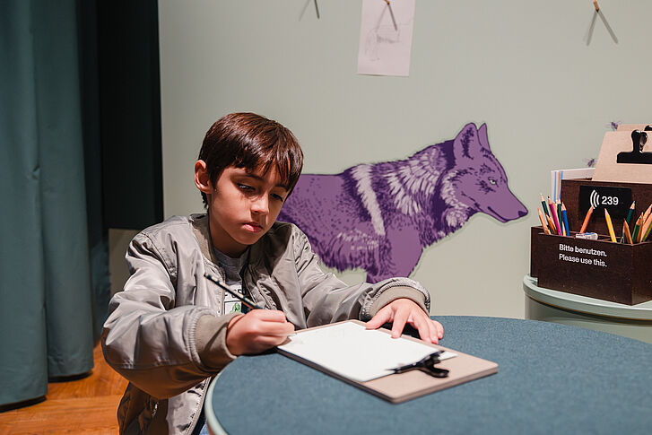 Ausstellungsansicht "Natur und deutsche Geschichte. Glaube – Biologie – Macht" Ein Junge in hellgrüner Jacke mal ein Bild, im Hintergrund die violette Zeichnung eines Wolfs