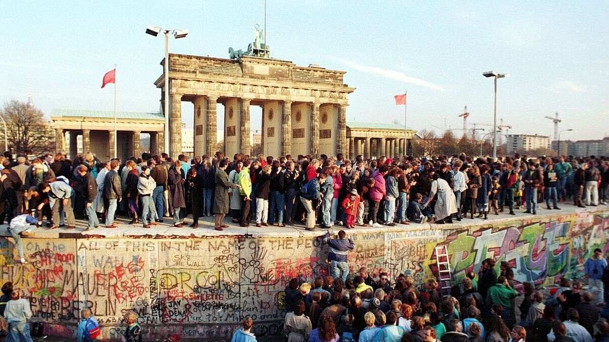 Menschen stehen auf der Berliner Mauer vor dem Brandenburger Tor am 10. November 1989.