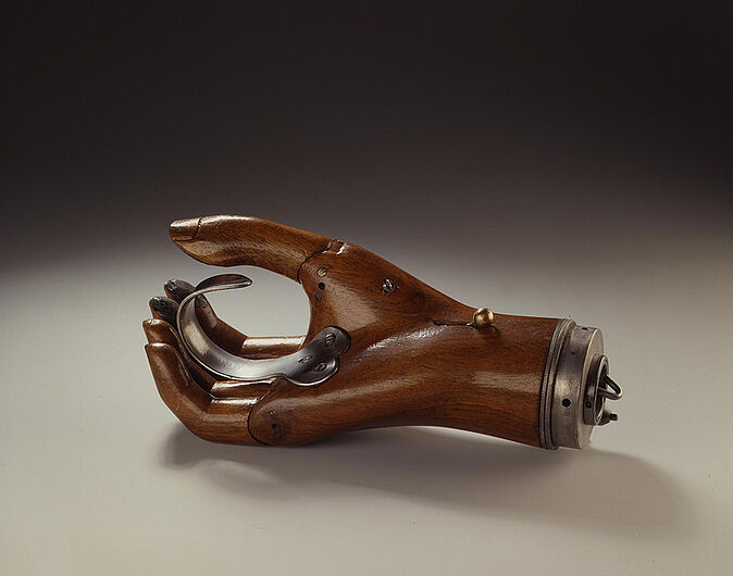 Handprothese (links), 1920/1930. Diese schmale Handprothese der linken Hand wurde auf eine Armprothese aufgeschraubt. Der Invalide konnte die Finger mittels eines Eisendrahthakens bewegen, der unter dem Ärmelansatz versteckt war. (Inv.Nr. 1989/1799)