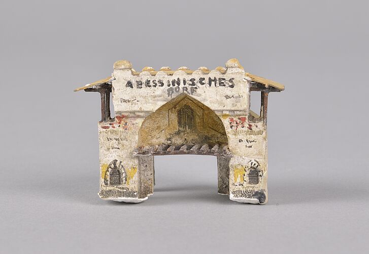 A miniature model of a gate against a grey background.