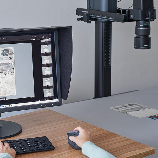 Eine Person bedient einen Computer und macht Fotoaufnahmen