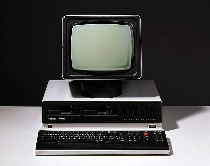 Personalcomputer „PC 1715“ mit Bildschirm, Tastatur, Kabeln und anderem Zubehör, vor 1989. Der Computer war der erste seit 1985 in Serie produzierte 8-Bit-Mikrorechner der DDR. 1986 stellte Robotron 21.000 Stück des Modells her. Es wurde vor allem in die Staaten des Ostblocks exportiert. (Inv.Nr. AK 99/23)