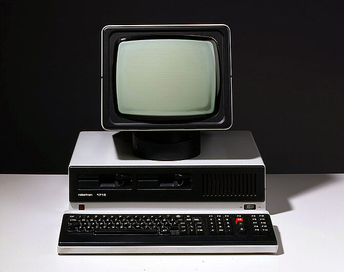 Personalcomputer „PC 1715“ mit Bildschirm, Tastatur, Kabeln und anderem Zubehör, vor 1989. Personalcomputer „PC 1715“ mit Bildschirm, Tastatur, Kabeln und anderem Zubehör, vor 1989. Der Computer war der erste seit 1985 in Serie produzierte 8-Bit-Mikrorechner der DDR. 1986 stellte Robotron 21.000 Stück des Modells her. Es wurde vor allem in die Staaten des Ostblocks exportiert. (Inv.Nr. AK 99/23)