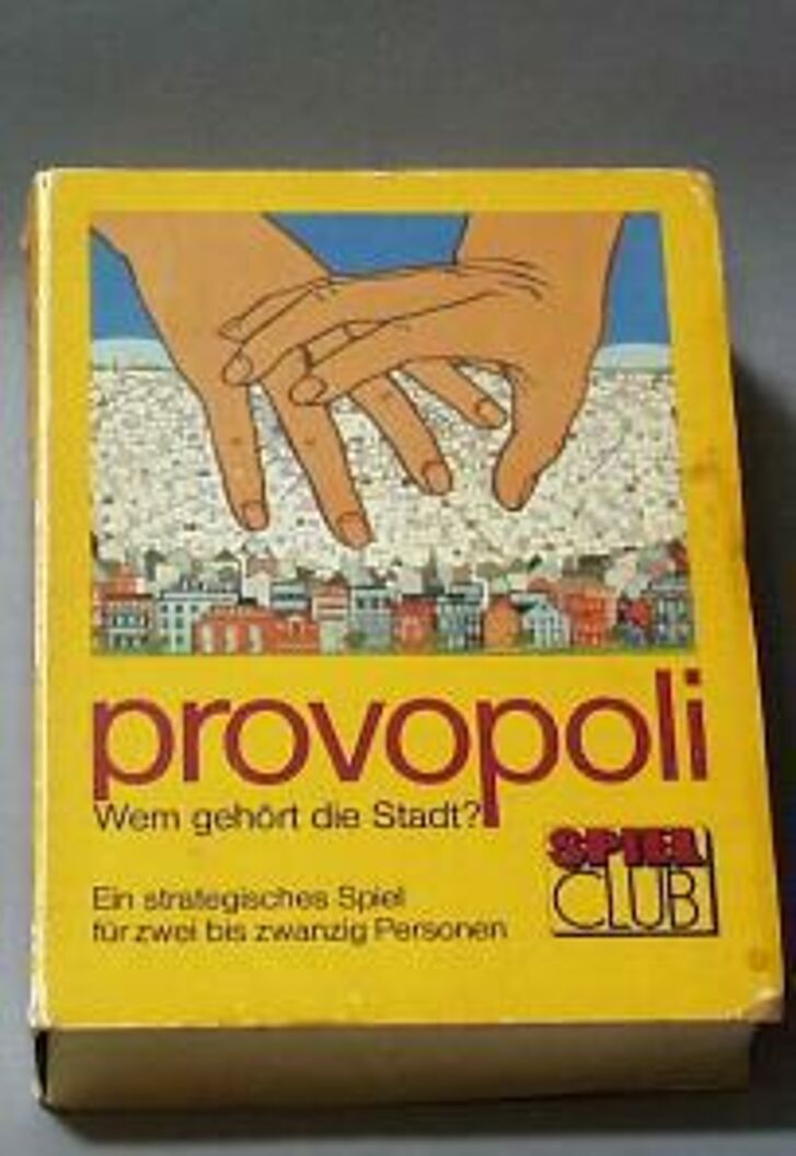 Schachtel mit Illustration von zwei Händen, die eine Stadt greifen wollen.