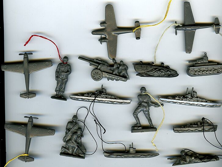 Abzeichen in Form von Waffen, Schiffen, Flugzeugen und Soldaten.