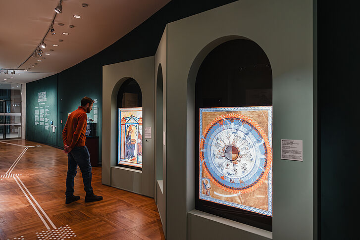 Exhibition view "Nature and German History. Faith – Biology – Power" Man in red sweater looks at the work “Weltenei” (World Egg) in the exhibition “Nature and German History. Faith – Biology – Power.”
