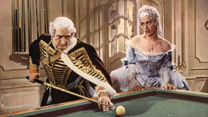 Eine Frau in einem historischen Gewand sieht einem Mann beim Billardspielen zu.