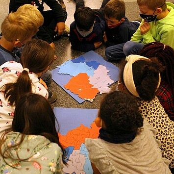 Kinder liegen am Boden und basteln.