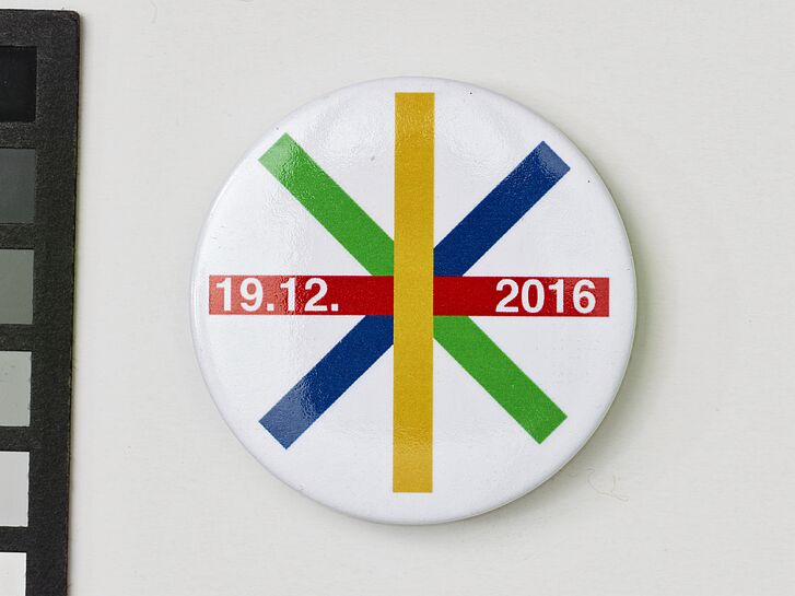 Button mit bunten Streifen und Datum.