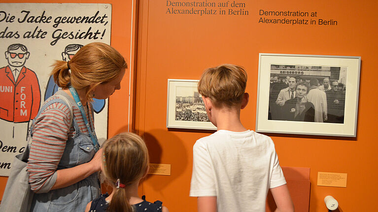 Eine Frau und zwei Kinder sehen sich eine Fotographie an.