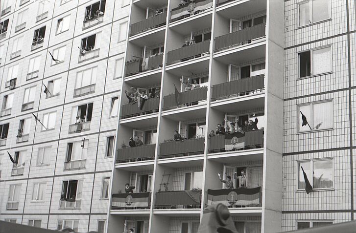 Menschen in einem Hochhaus versammeln sich auf Balkonen.