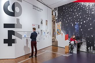Besucher stehen vor einer großen Kunstanzeige und sind fasziniert von den kreativen Darstellungen.