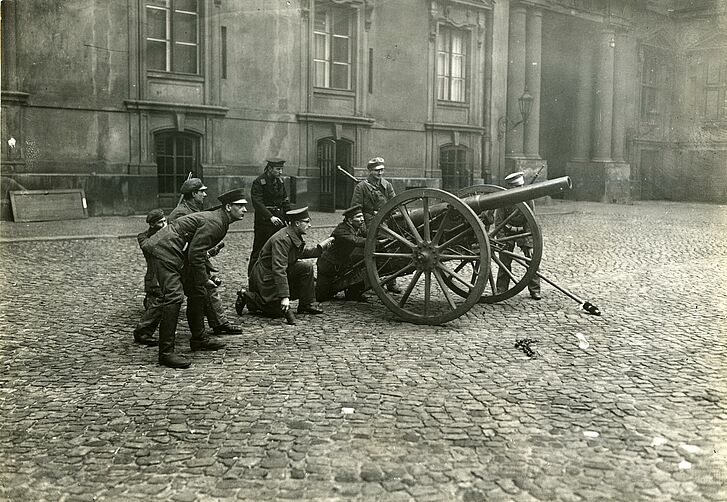 Soldaten stehen und knien hinter einer Kanone.