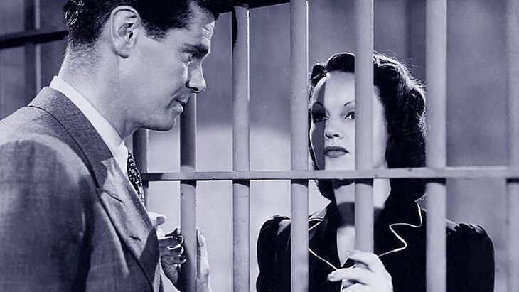 Ein Mann redet mit einer Frau hinter Gittern.