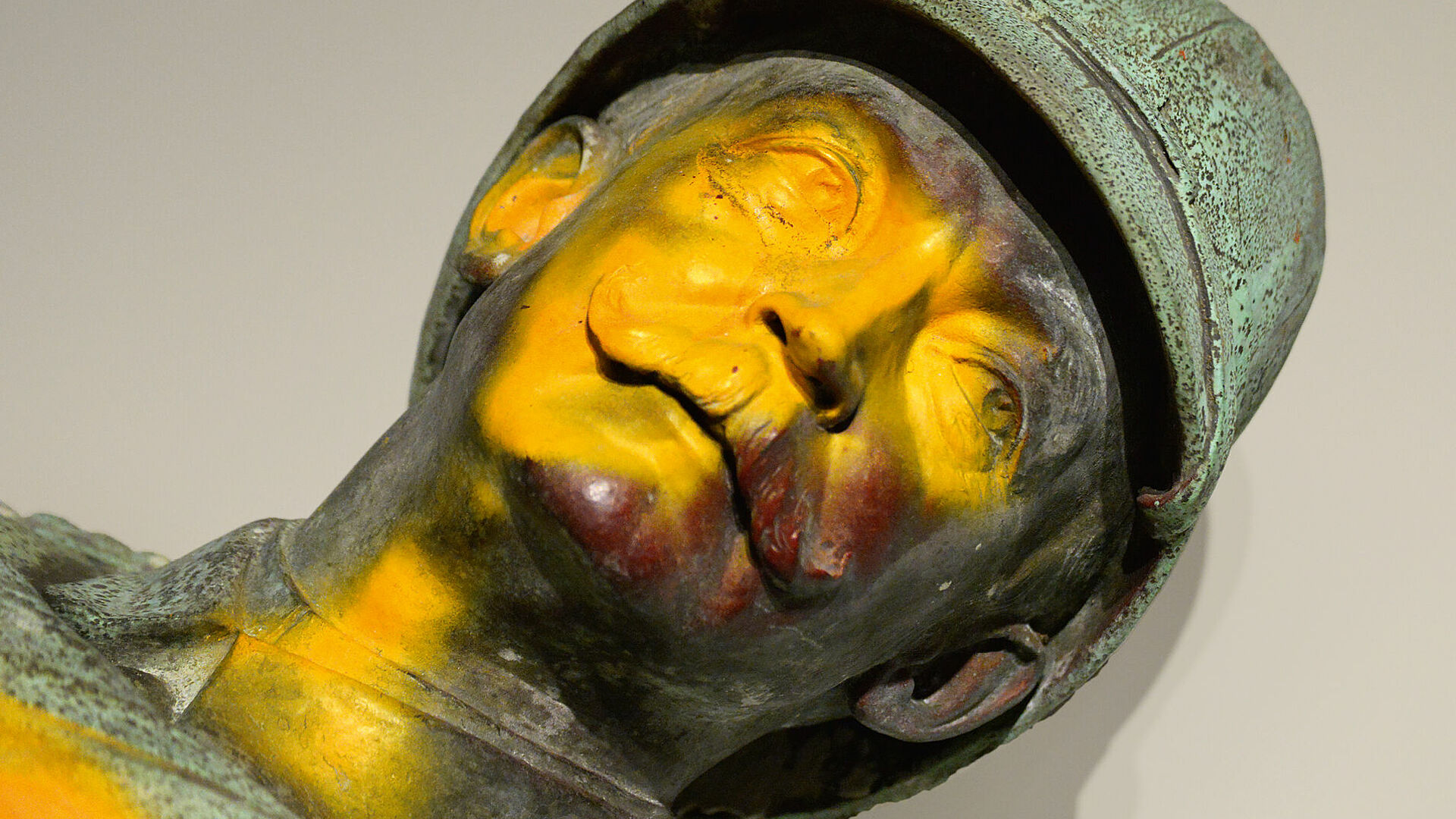 Kopf einer verfärbten Bronzeskulptur eines Mannes mit Bart und Helm.