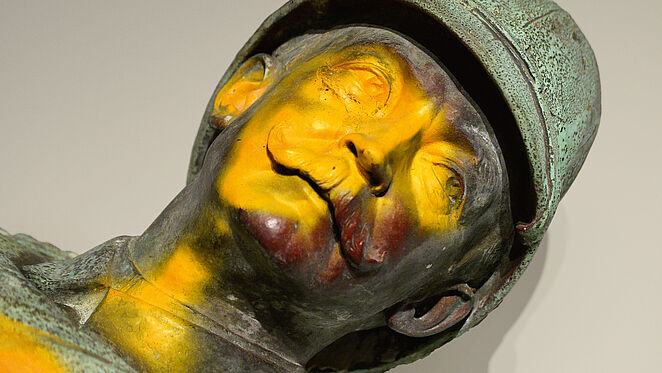Kopf einer verfärbten Bronzeskulptur eines Mannes mit Bart und Helm.