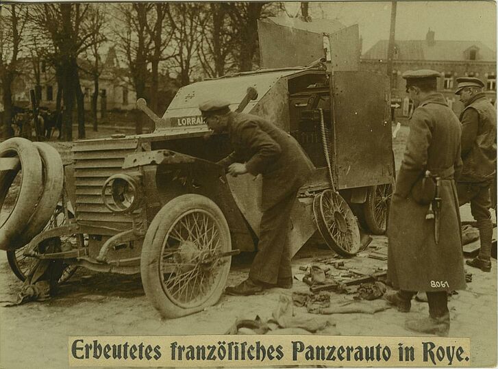 Ein Mann betrachtet ein Panzerauto.