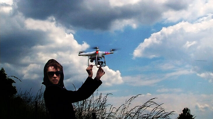 Sibylle Berg hat eine Drohne in den Händen und blickt in die Kamera.