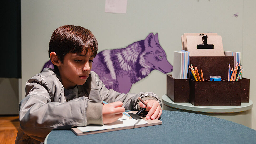 Ein Kind malt etwas auf ein Blatt Papier