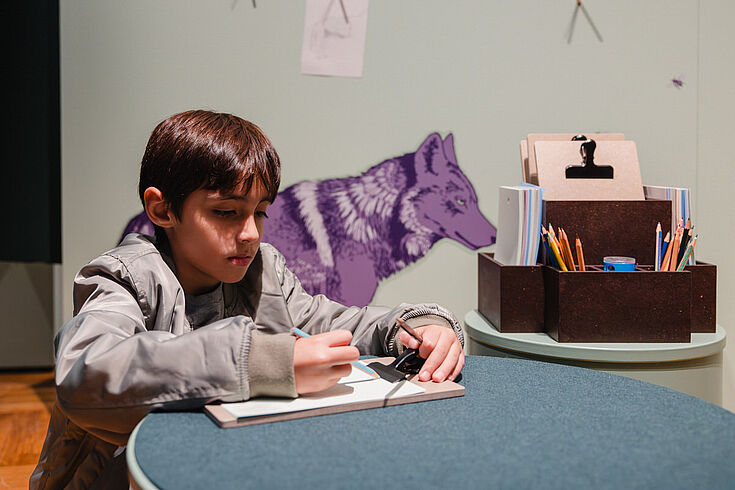 Ein Kind malt etwas auf ein Blatt Papier