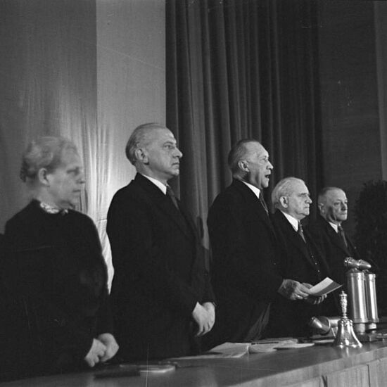 Eine Gruppe von Personen versammelt sich um einen Tisch mit einem Mikrofon für ein Gespräch oder eine Besprechung.