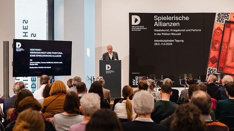 Thomas Weißbrich steht hinter einem Pult und spricht zum Publikum.