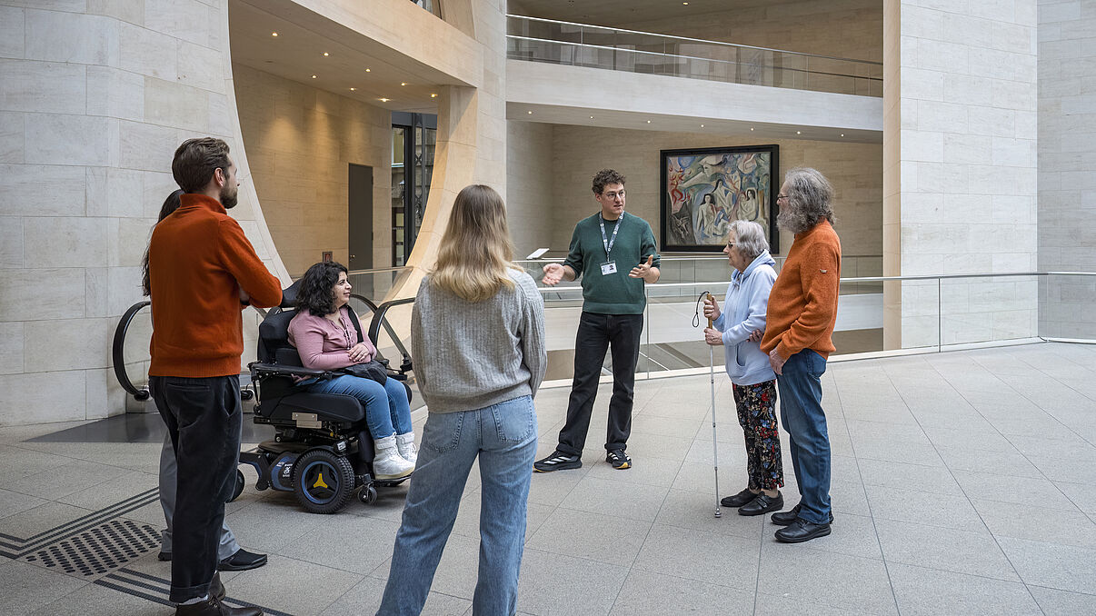 Mehrere Personen befinden sich in einem Foyer eines Museums