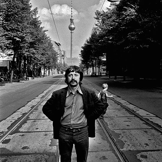 Wolf Biermann steht auf der Strasse und hinter ihm sieht man den Fernsehturm.