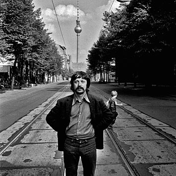 Wolf Biermann steht auf der Strasse und hinter ihm sieht man den Fernsehturm.
