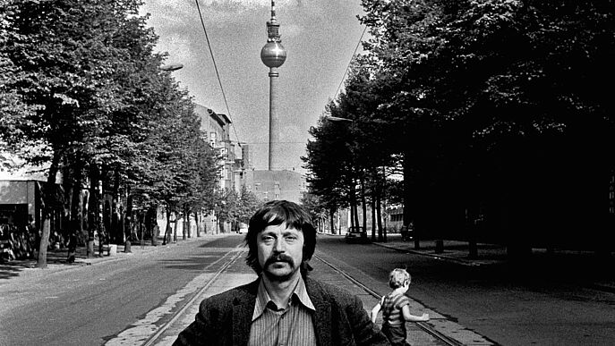 Wolf Biermann steht auf der Strasse und hinter ihm sieht man den Fernsehturm.