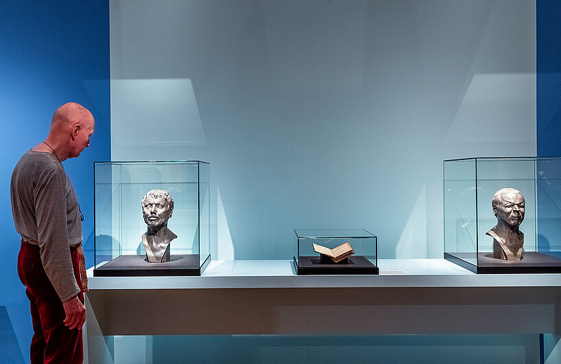 Ein Mann betrachtet eine männliche Büste in einer Vitrine.