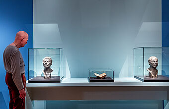 Ein Mann betrachtet eine männliche Büste in einer Vitrine.