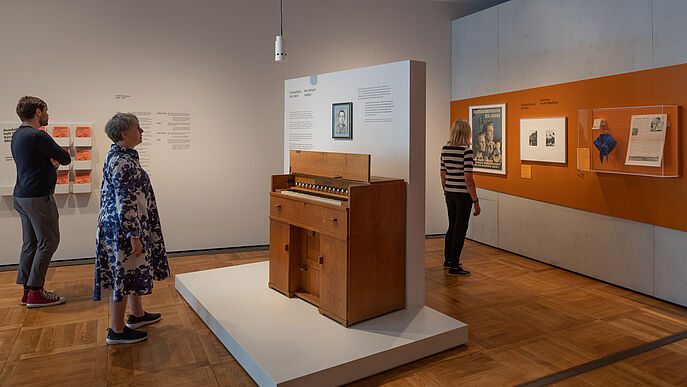 Drei Personen schauen sich die Ausstellung an.
